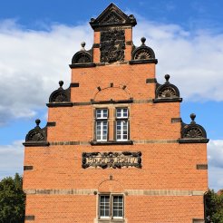 Das Bild zeigt den Giebel des alten Magazinbaus im Stil der Neorenaissance mit dem in Stein gemeisselten Schriftzug "Staatsarchivs Münster".